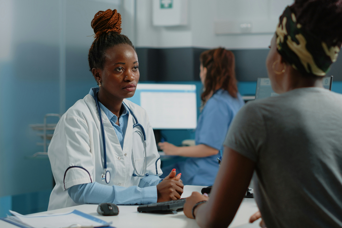 Making your healthcare appointments accessible for Deaf people: two women sit facing each other in a healthcare setting.