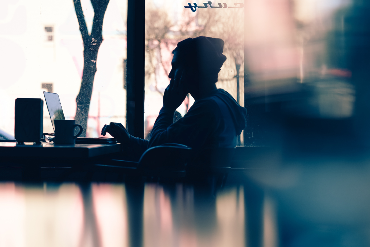 Wellbeing at work: a person sits by a giant window working with the light behind them.