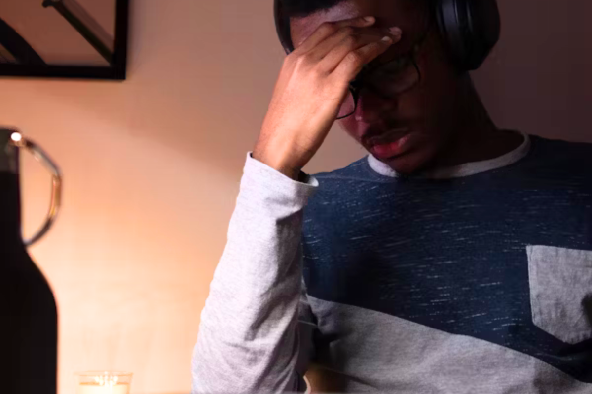 Internalised ableism and neurodiversity: A man sits holding his head and wearing a pair of headphones