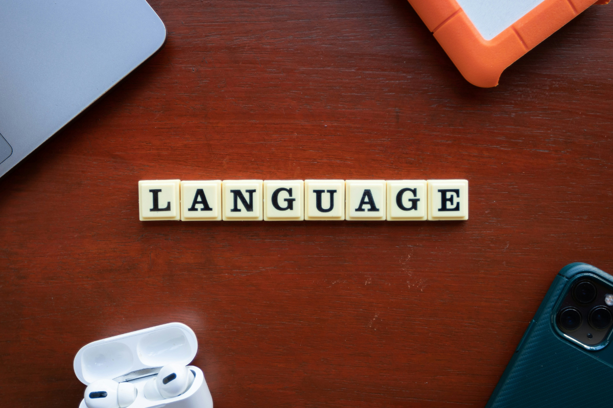 Inclusive language: A row of letters from a scrabble board spelling out language surrounded by headphones, a laptop